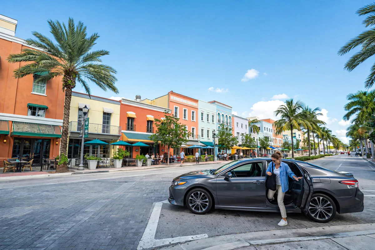 Rideshare pickup on a downtown West Palm Beach, Florida street lined with palm trees — Rafferty Domnick Cunningham & Yaffa