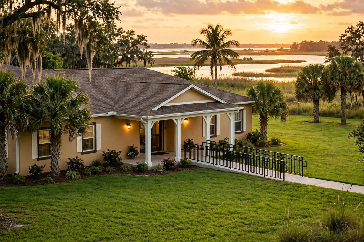 Welcoming single-story nursing home residence with palm trees and a covered entrance in Belle Glade, Florida — Rafferty Domnick Cunningham & Yaffa